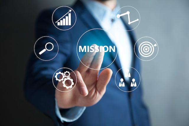 Hand touching a Mission button surrounded by business strategy icons